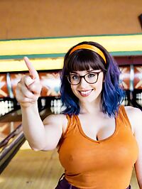A tall muscular woman with big tits stands alone in the dimly lit bowling alley