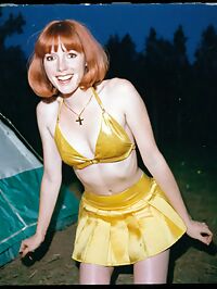 Woman dressed in 1970s era fashion lies naked on her back in a camping tent
